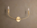 Arnett Double Sconce with an antiqued gold finish, featuring a round backplate and two candle-style lights on a curved arm.