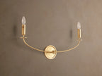 Arnett Double Sconce with an antiqued gold finish, featuring a round backplate and two candle-style lights on a curved arm.