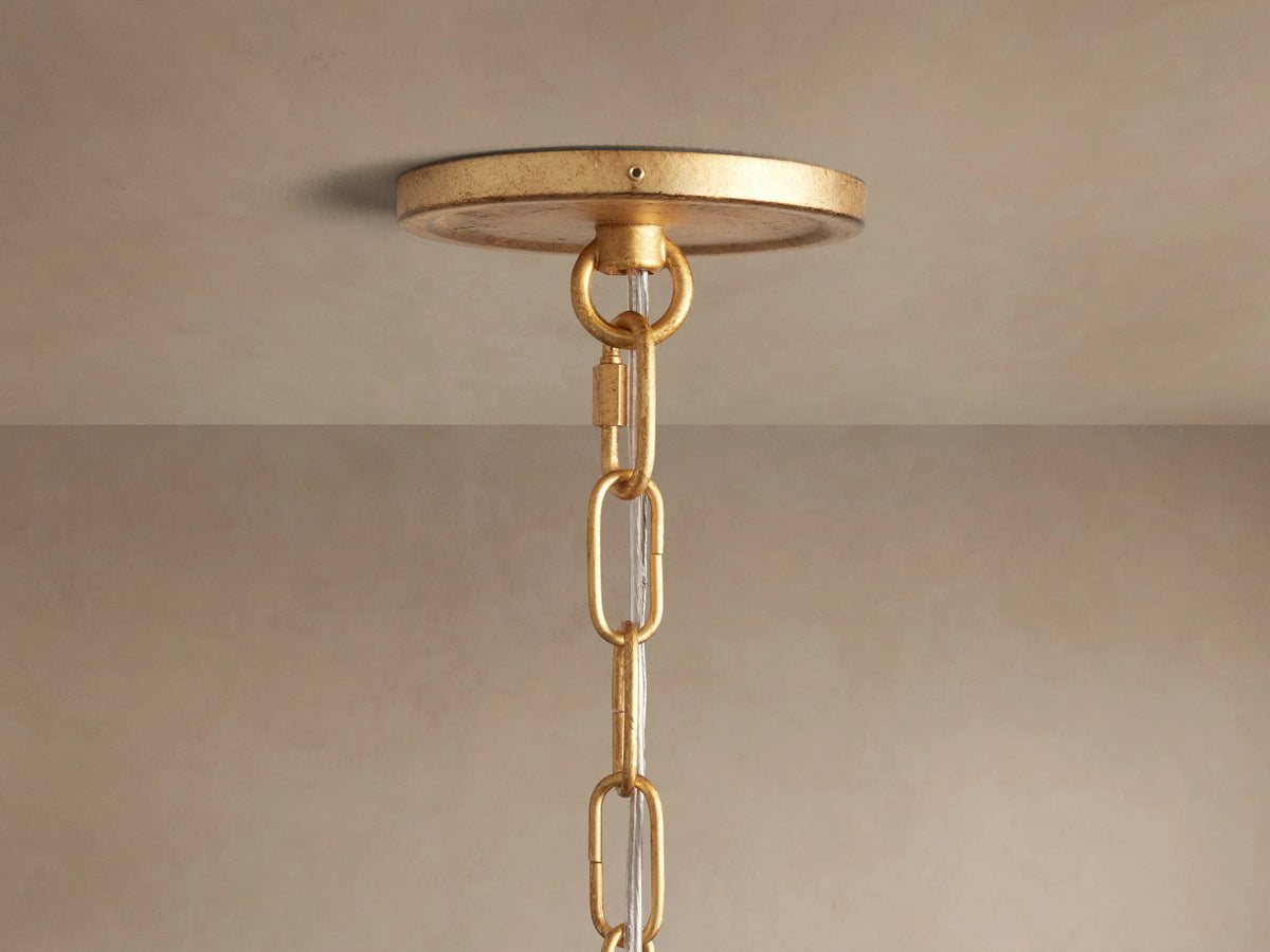 Arnett Chandelier's antiqued gold round canopy, chain, and clear cord, seen mounted on a light-colored ceiling.