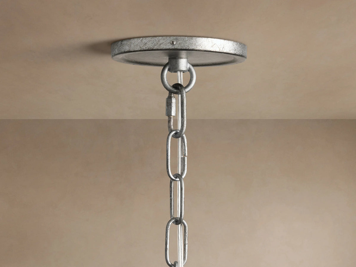Close-up of Arnett Round Chandelier with antiqued leaf finish, showing three illuminated candle-style bulbs and curved metal arms.
