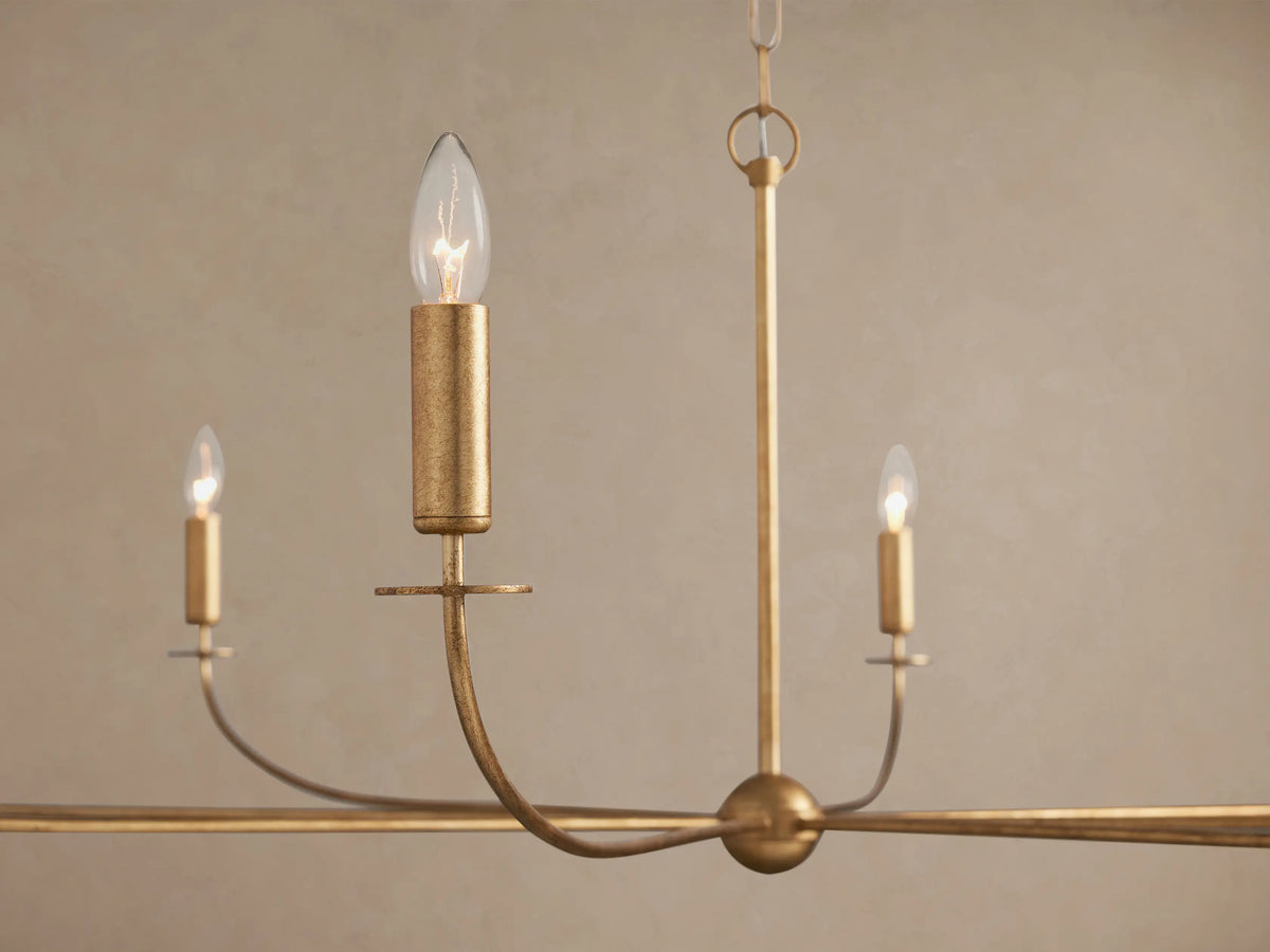 Arnett Chandelier close-up: antiqued golden iron frame, curved arms, and three illuminated candle-style bulbs.