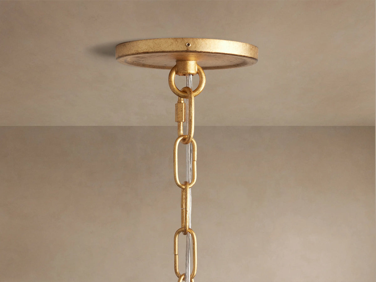 Close-up of Arnett Chandelier's round antiqued golden ceiling canopy and top chain links with clear cord against a beige ceiling.