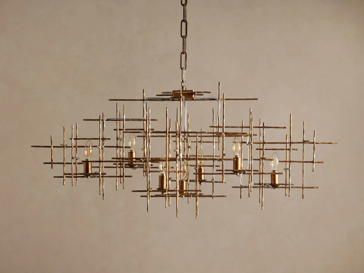 Fritz Chandelier: Hand-hammered antique gold iron rectangular chandelier with an intricate grid design and seven exposed, lit bulbs.