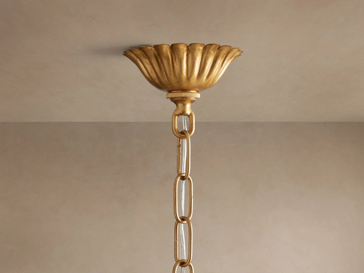 Close-up of Matilde Pendant, an ornate antique-gold iron light fixture with overlapping, textured petals glowing warmly.