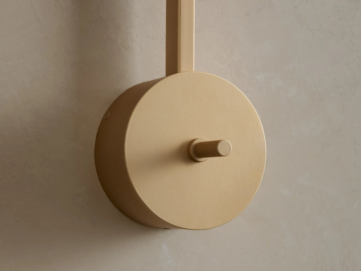 Costella Grand Sconce: Close-up of softly glowing round opal glass diffuser on vertical champagne gold arm.