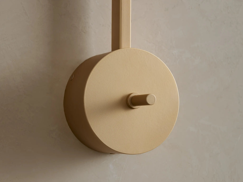 Costella Grand Sconce: Close-up of softly glowing round opal glass diffuser on vertical champagne gold arm.