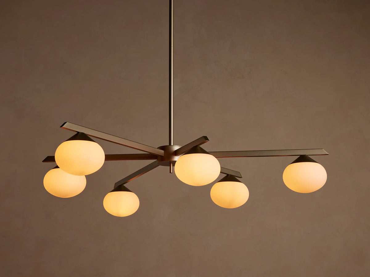 Costella Round Chandelier with six illuminated opal glass globe diffusers on champagne finish iron arms, hanging from above.