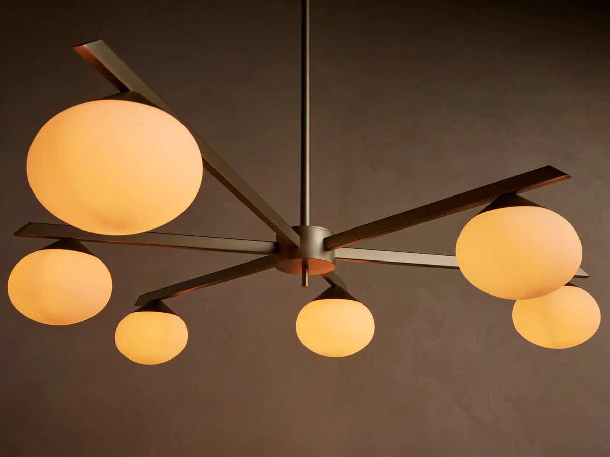 Costella Round Chandelier: Gold iron frame with six radiating arms, each holding a round white opal glass diffuser, against a light wall.