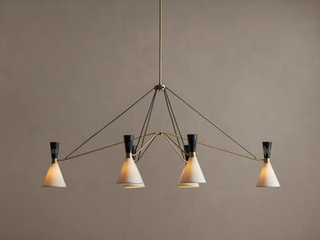 Ramsey Linear Chandelier with a satin brass frame, matte black accents, and six glowing white conical fabric shades.