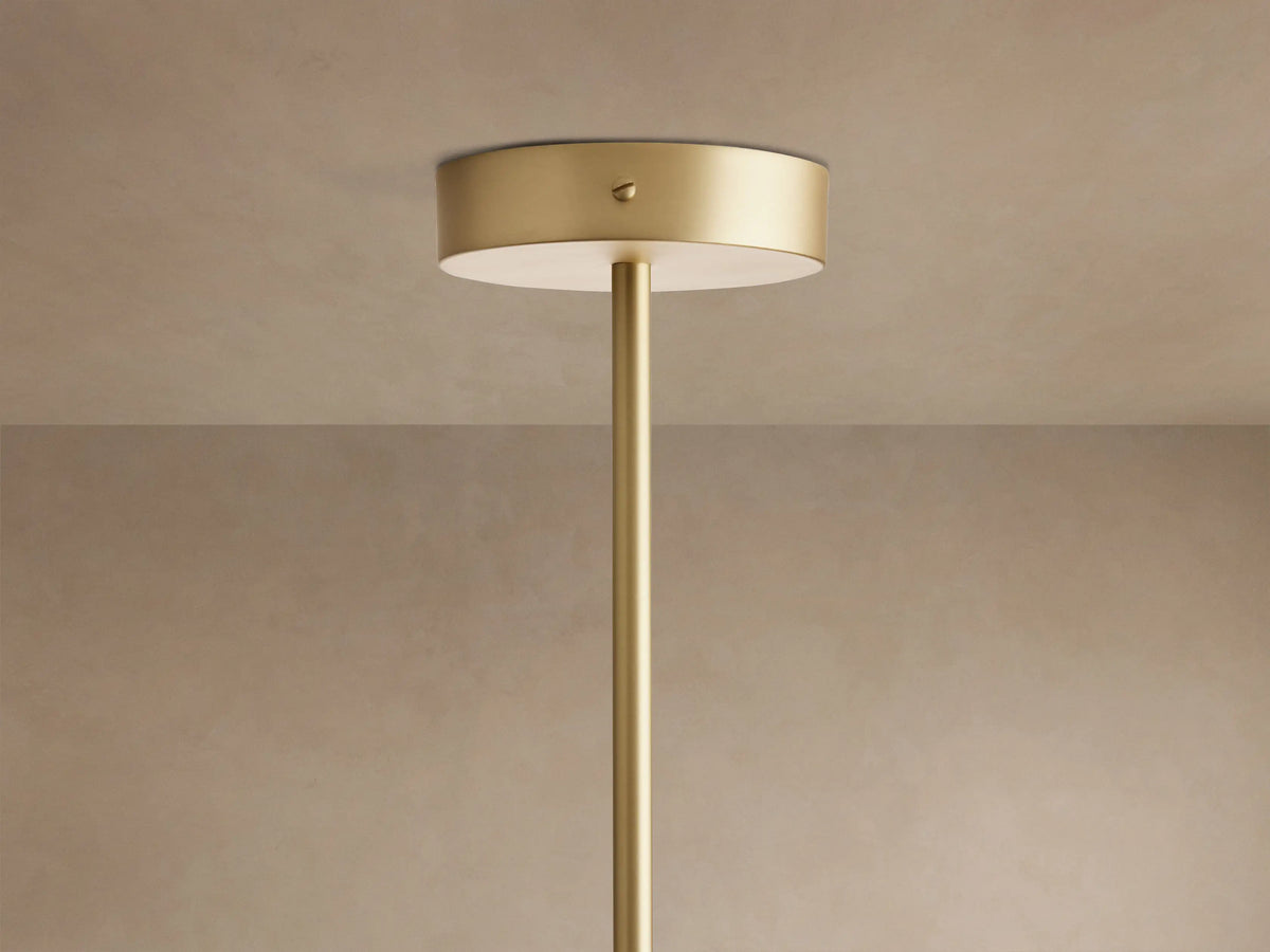 Close-up of Ramsey Linear Chandelier with brass frame, black metal accents, and three glowing white fabric cone shades.