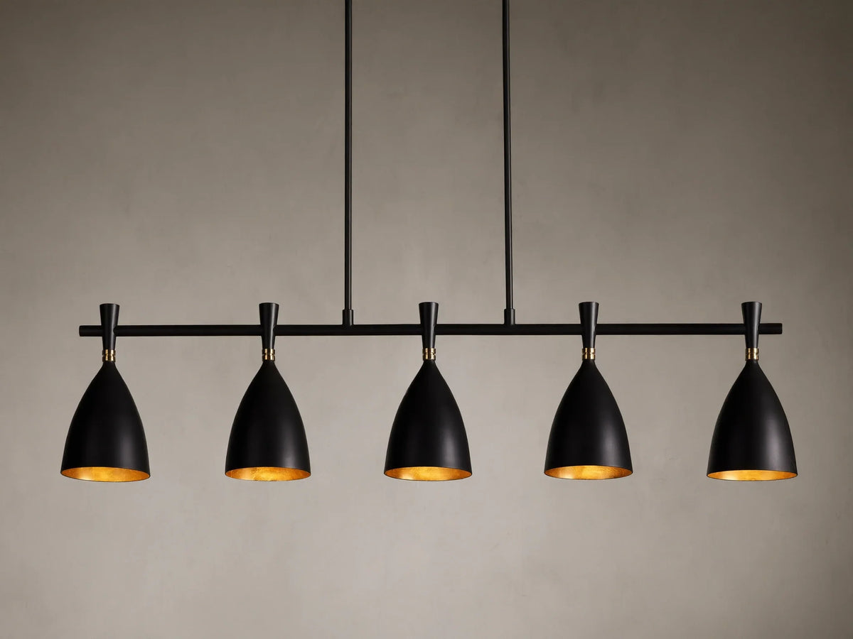 Jacarra Linear Chandelier with five black metal shades, gold leaf interior, hanging from an old bronze rod against a gray background.