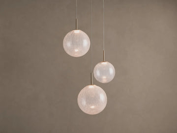 Casen Round Chandelier. Three illuminated crackle glass globes with satin brass accents, suspended at varying heights.