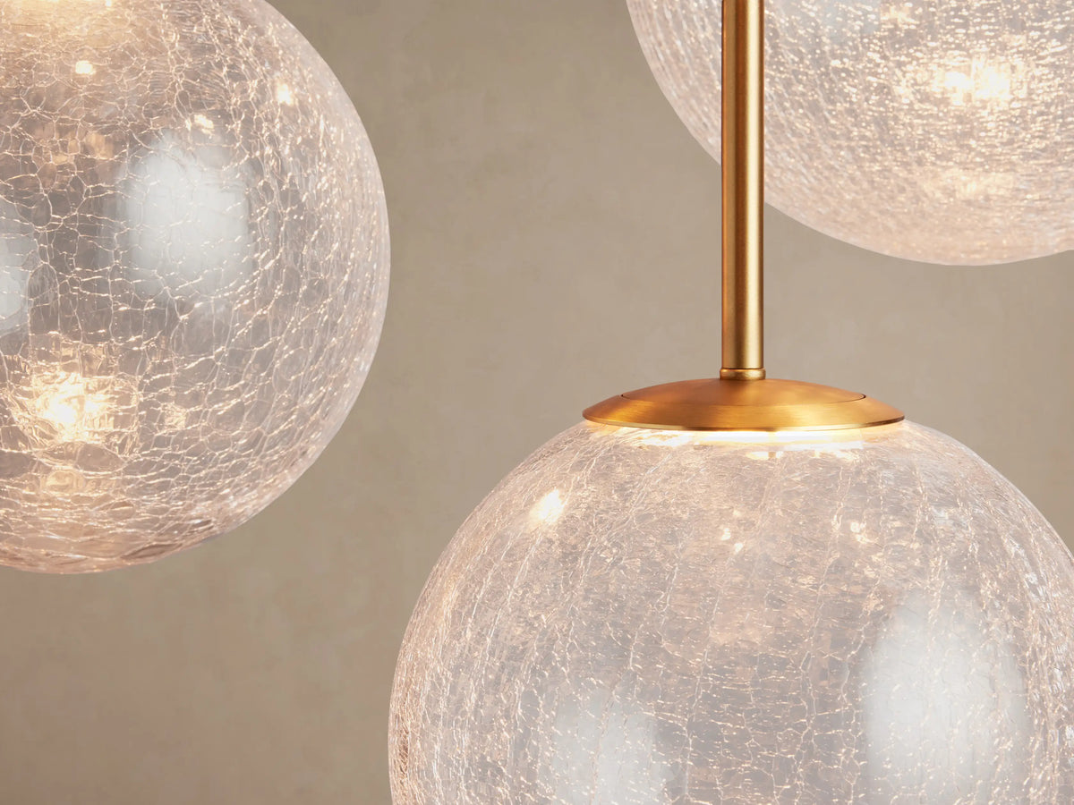 Casen Round Chandelier: Close-up of glowing crackle glass globes with textured surface and a bright satin brass fitting.