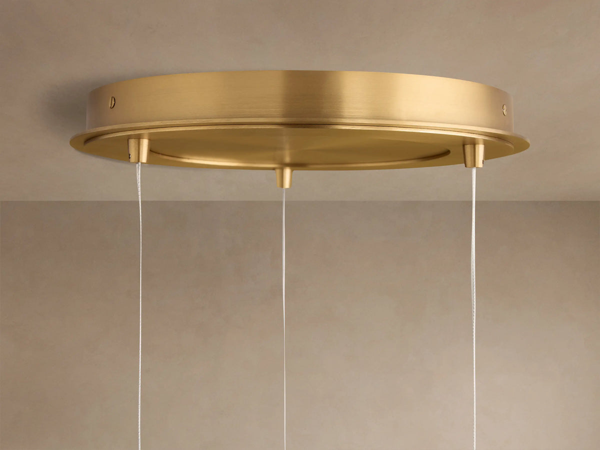 Casen Round Chandelier ceiling plate, satin brass, flush-mounted on a light ceiling, with three thin white suspension cables.