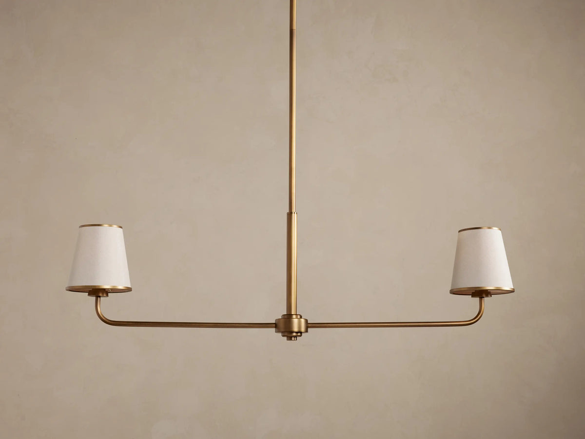 Adria 2-Light Chandelier: Bronze-finished frame with two glowing, tapered off-white fabric shades on a horizontal bar.