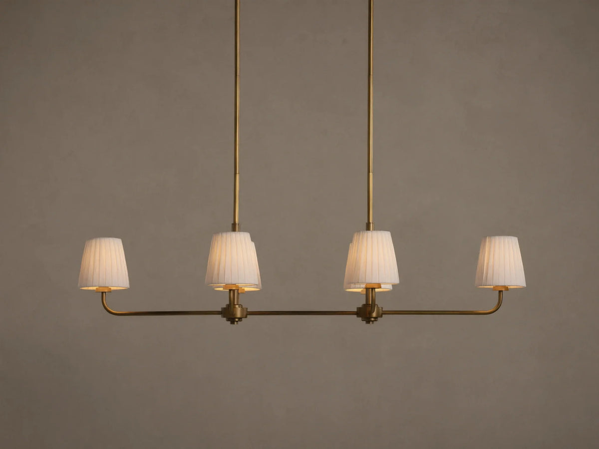 Adria Linear Chandelier with 4 illuminated pleated white shades on a horizontal brass bar, hanging from 2 brass rods.