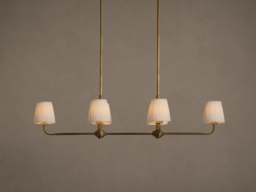 Adria Linear Chandelier with 4 illuminated pleated white shades on a horizontal brass bar, hanging from 2 brass rods.
