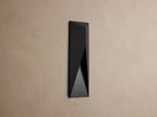Modern dark grey Davian Outdoor Sconce, vertically mounted, with geometric facets and warm bronze light emanating from inside.