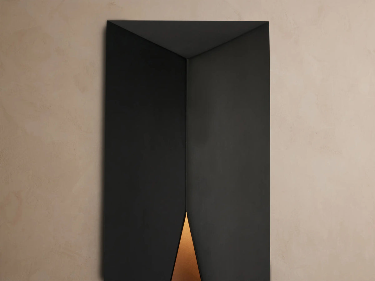 Davian Outdoor Sconce, a sleek black rectangular light with geometric angled front, mounted vertically on a light beige wall.