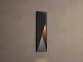 Modern dark grey Davian Outdoor Sconce, vertically mounted, with geometric facets and warm bronze light emanating from inside.