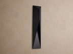 Black, geometric Davian Outdoor Sconce with a bronze interior accent, mounted vertically on a light brown wall.