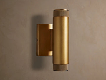 Vertical brass Spotlight Outdoor Sconce, cylindrical, mounted on a wall, with knurled end caps, emitting light up and down.
