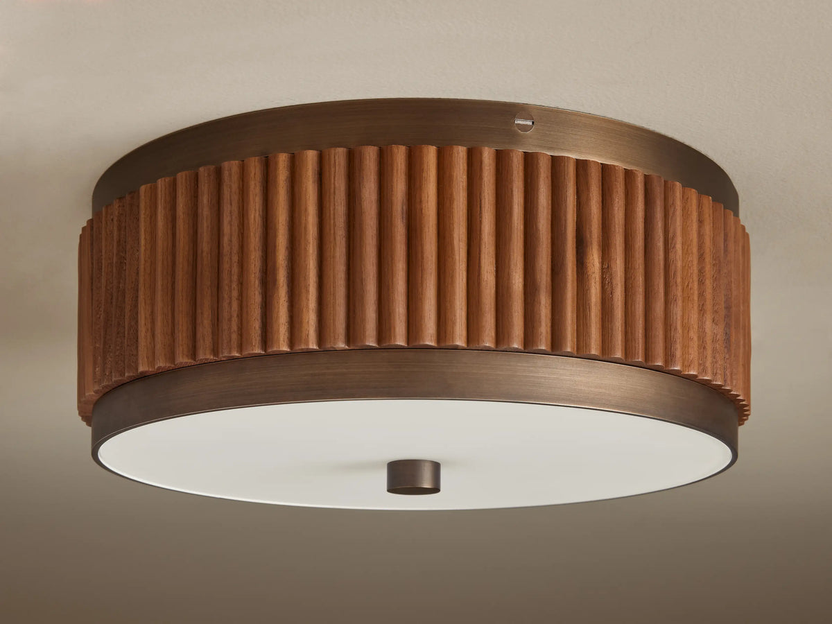 A circular ceiling lamp with a wooden, ribbed outer finish and a smooth, white frosted diffuser, emitting a warm light.