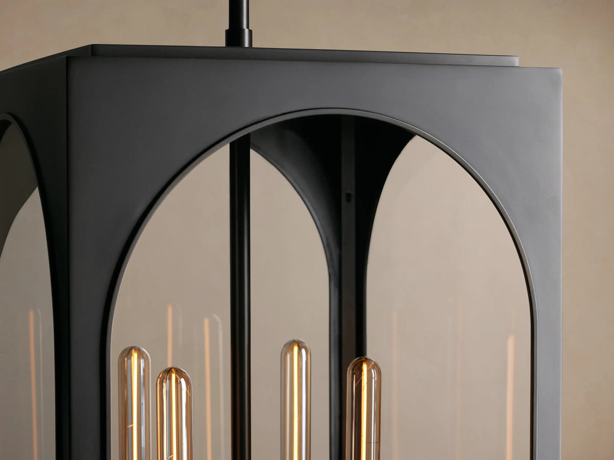 Black Palladian Outdoor Pendant, a hanging lantern with arched clear glass panels & three tubular bulbs, against a beige wall.