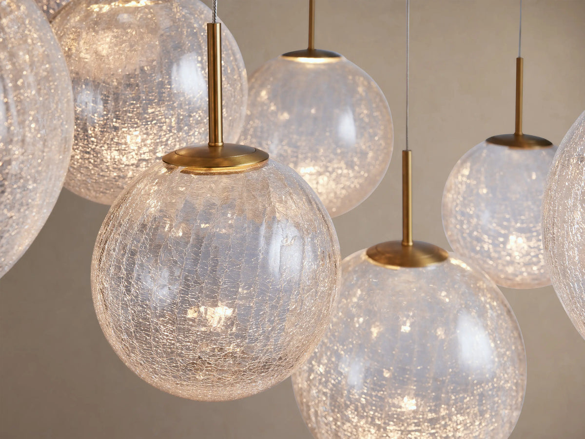 A close-up of the Casen Round Chandelier featuring multiple illuminated crackle glass globes with satin brass accents.