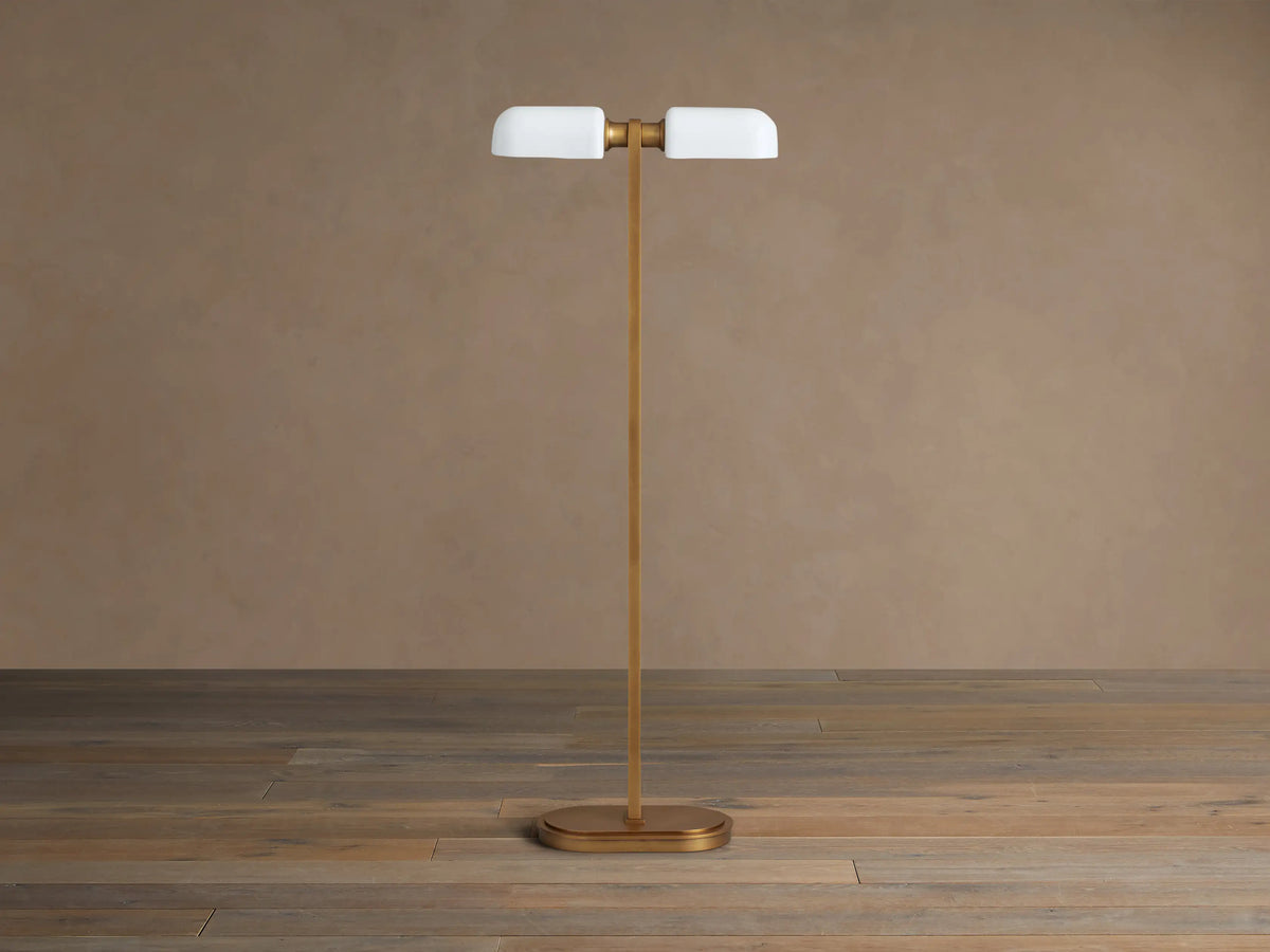 Zayd Floor Lamp: elegant brass with two illuminated oblong opal glass shades and an oval base, standing on a wooden floor.