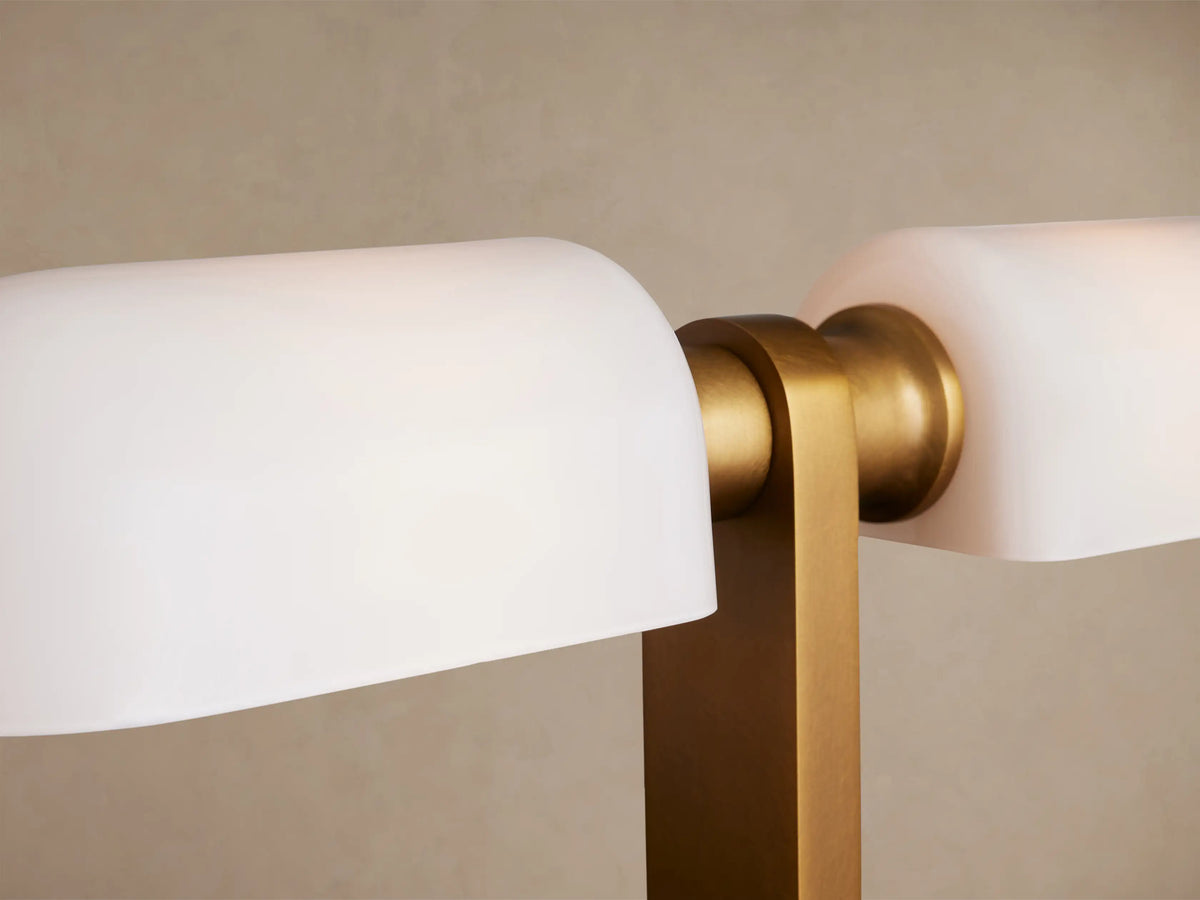 Zayd Table Lamp: Brass body with two rectangular opal glass shades, on a rustic wooden table against a neutral wall.
