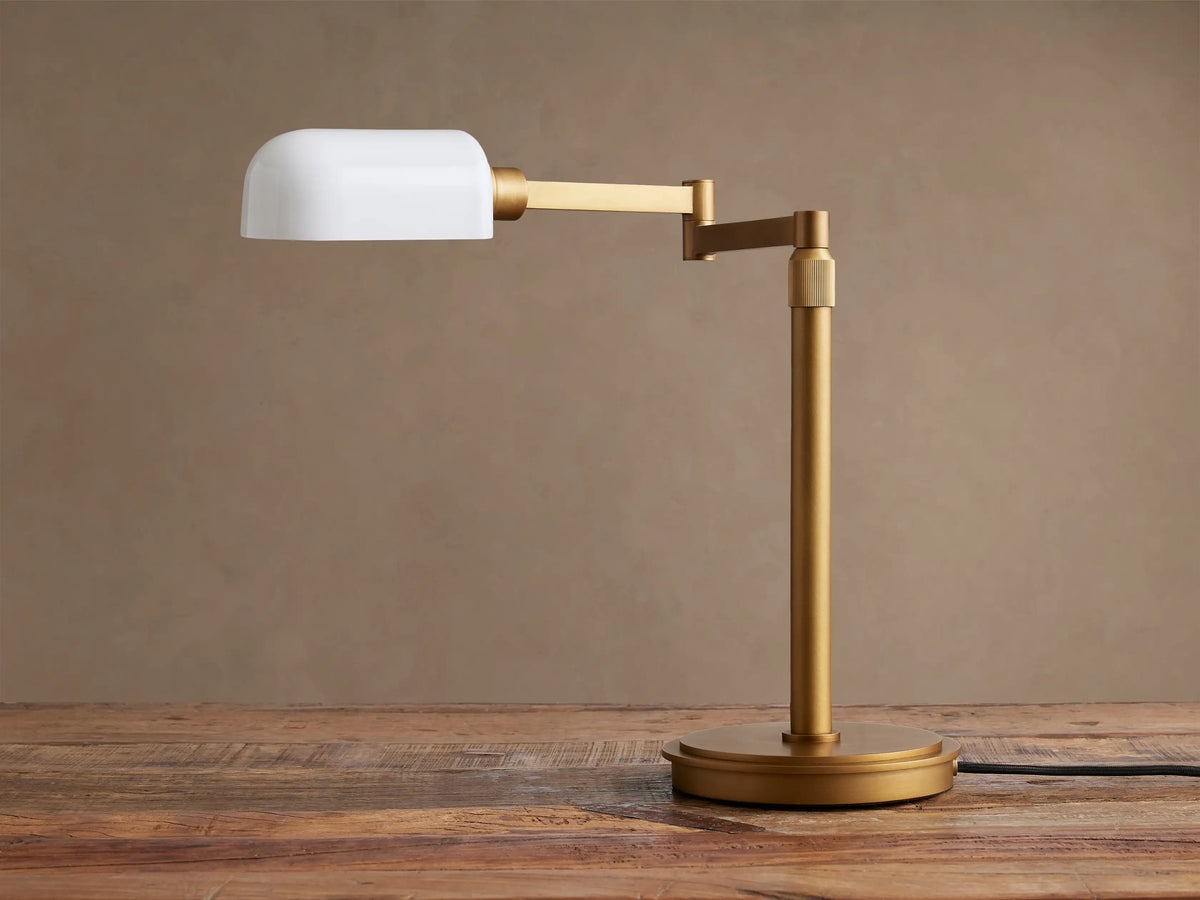 Zayd Swing Arm Table Lamp: Brass-finished body, swing arm extended horizontally with an illuminated opal glass shade.