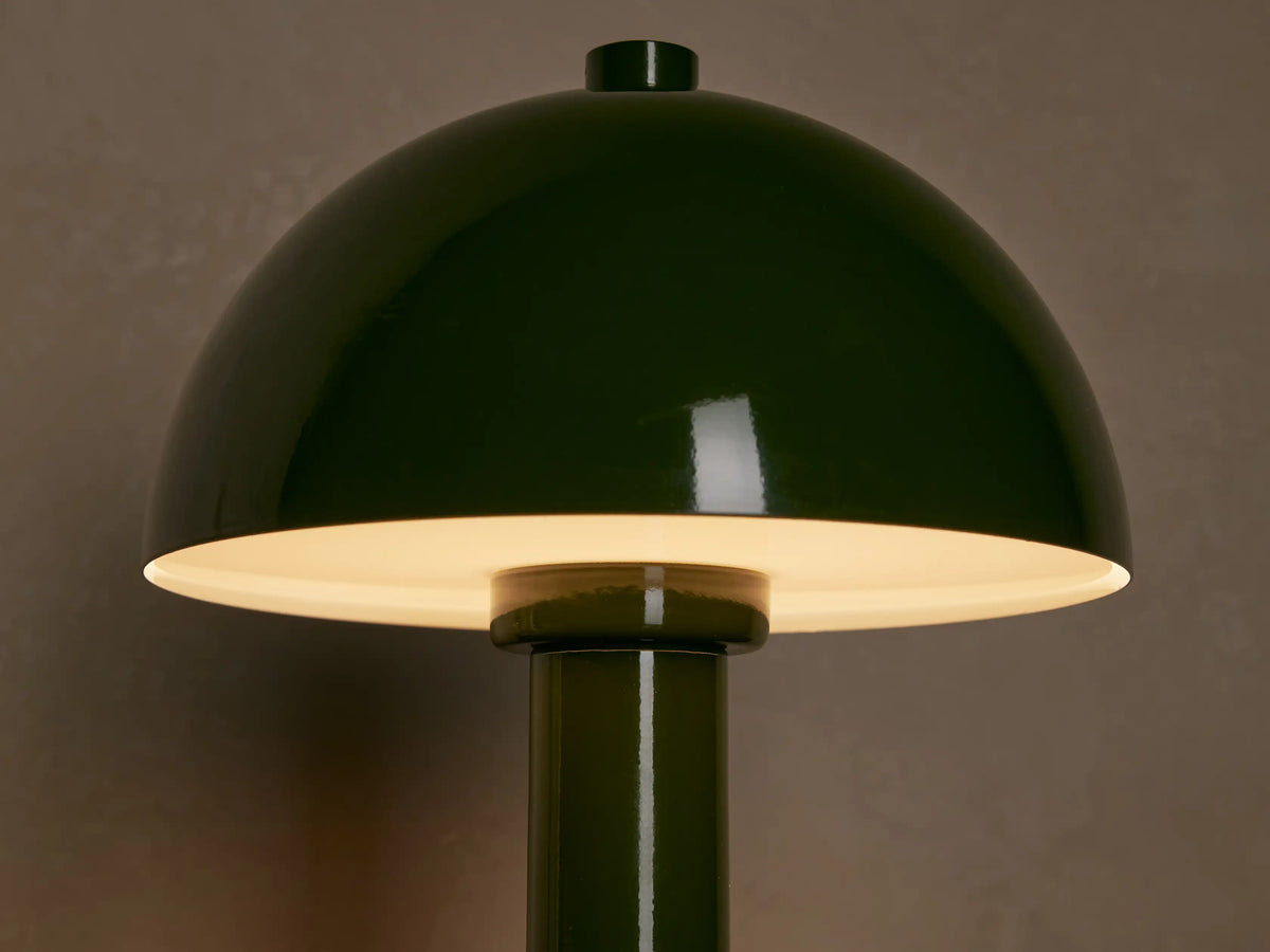 Green lacquered Jocy Portable Table Lamp with a mushroom-domed shade and cylindrical base on a wooden surface.