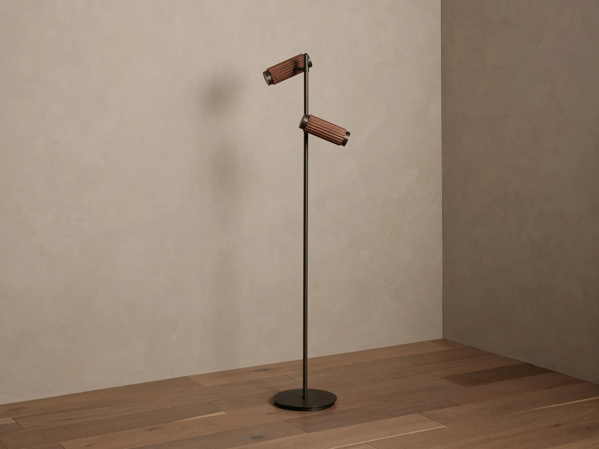 Decan Task Floor Lamp: bronze metal, two fluted walnut wood shades, one illuminated, casting a warm glow.