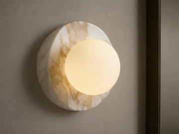 Corinna Sconce: Wall-mounted, round white and tan veined marble backplate with an illuminated milk glass globe.