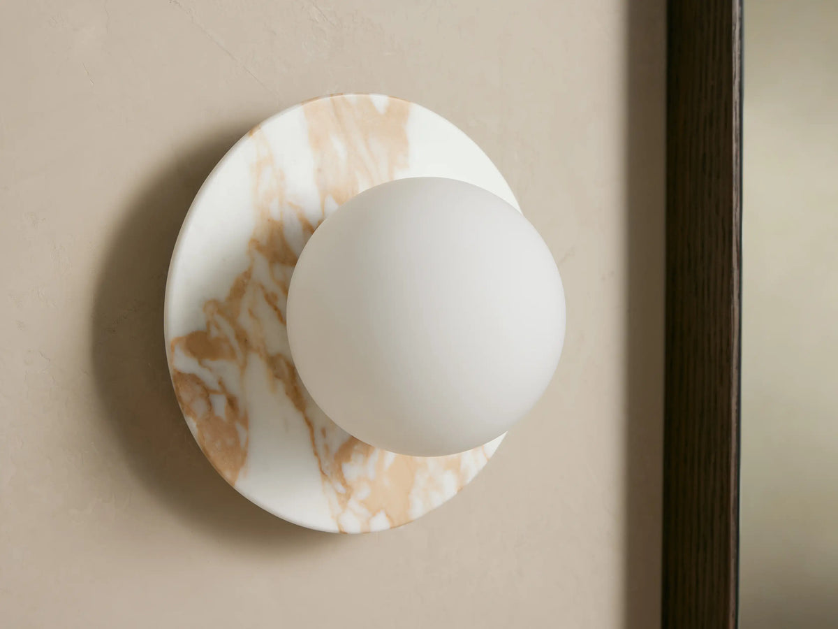 Corinna Sconce: Wall-mounted, round white and tan veined marble backplate with an illuminated milk glass globe.