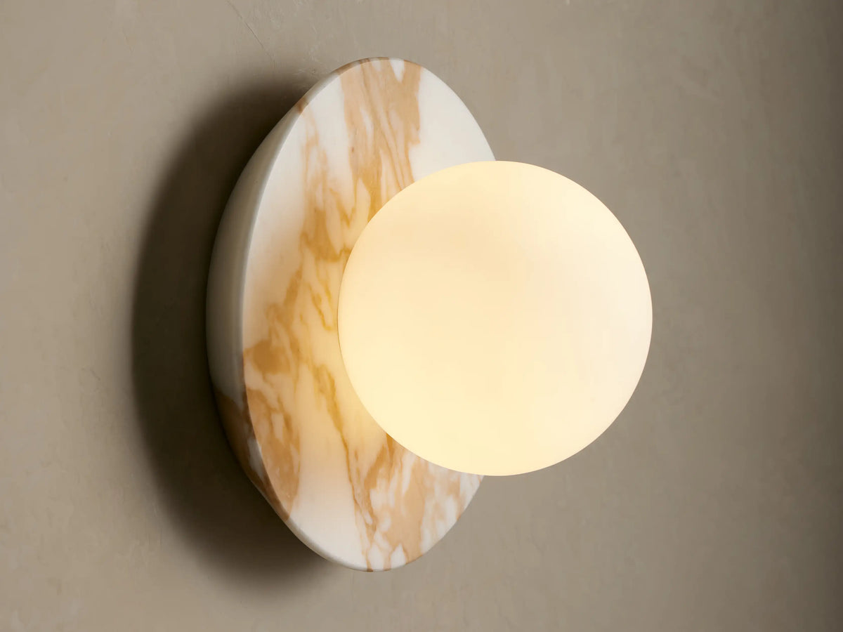Corinna Sconce: white marble circular wall light with tan veins, fronted by a white spherical milk glass globe.
