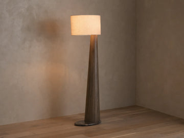 Front view of a tall floor lamp with a dark brown tapered wood base and a light beige rectangular fabric shade, emitting warm light.