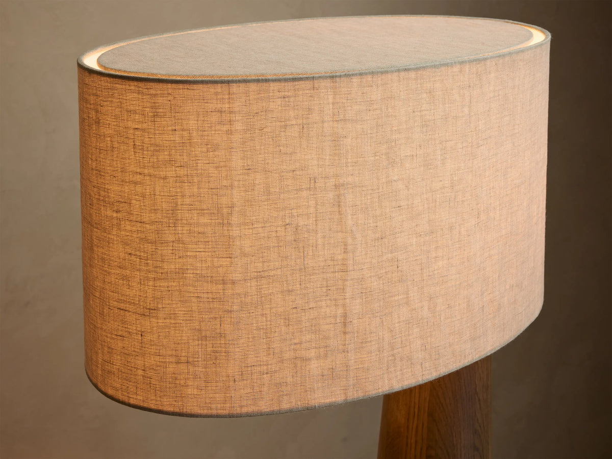 Front view of a tall floor lamp with a dark brown tapered wood base and a light beige rectangular fabric shade, emitting warm light.