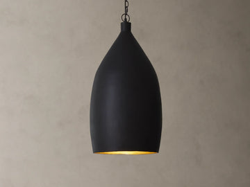 A matte black pendant light with a smooth, teardrop shape hanging from a chain against a beige textured wall.