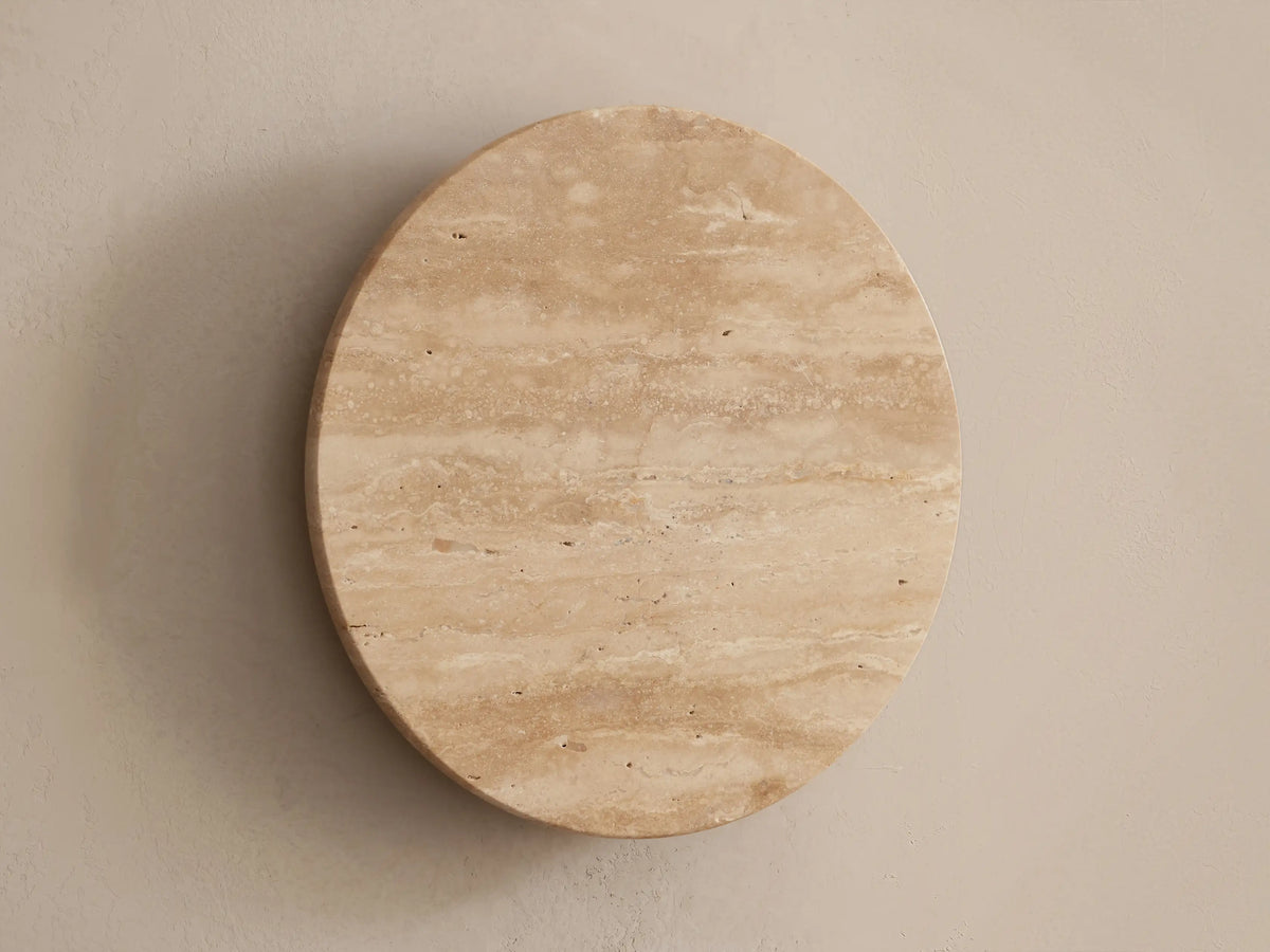 Odette Outdoor Sconce: Oval natural stone sconce with horizontal patterns, emitting a warm LED glow on a beige wall.