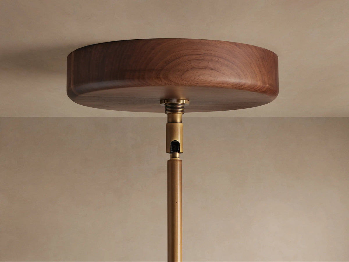 Alastair Pendant. Close-up of circular burnished brass shade with white acrylic diffuser, supported by geometric brass arms.