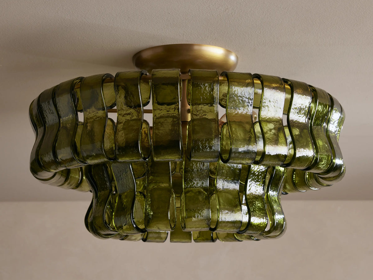Ghiaccio Flush Mount: Brass ceiling light with a two-tiered, wavy shade of textured olive green glass strips, emitting a warm glow.