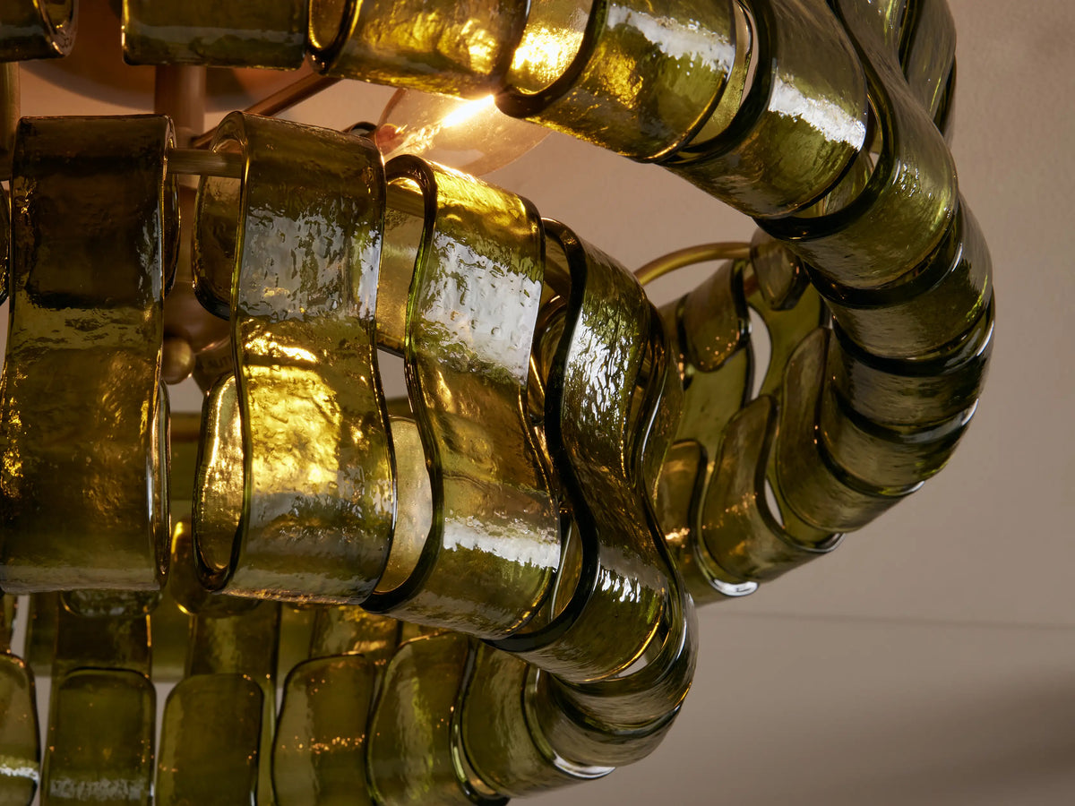 Ghiaccio Flush Mount with layered, wavy olive green textured glass pieces and a round brass ceiling mount on a light ceiling.