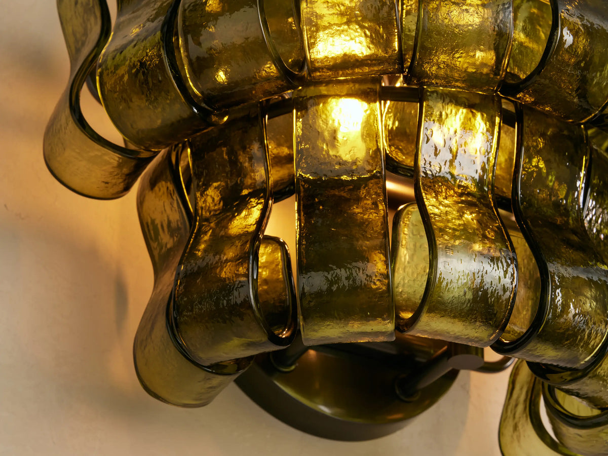 Ghiaccio Sconce: layered wall-mounted light with wavy, textured dark green curved glass panels on a light wall.