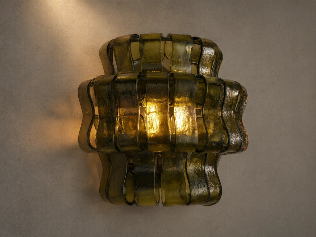 Ghiaccio Sconce: Dark green wavy textured glass wall sconce, glowing warmly, mounted on a light-colored wall.
