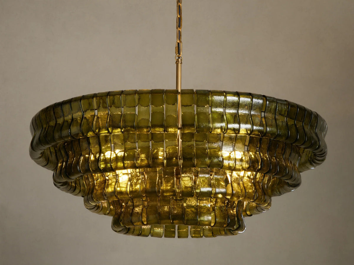 Ghiaccio Round Chandelier, dark green curved glass in tiered wavy layers, illuminated with warm golden light, hanging from chain.
