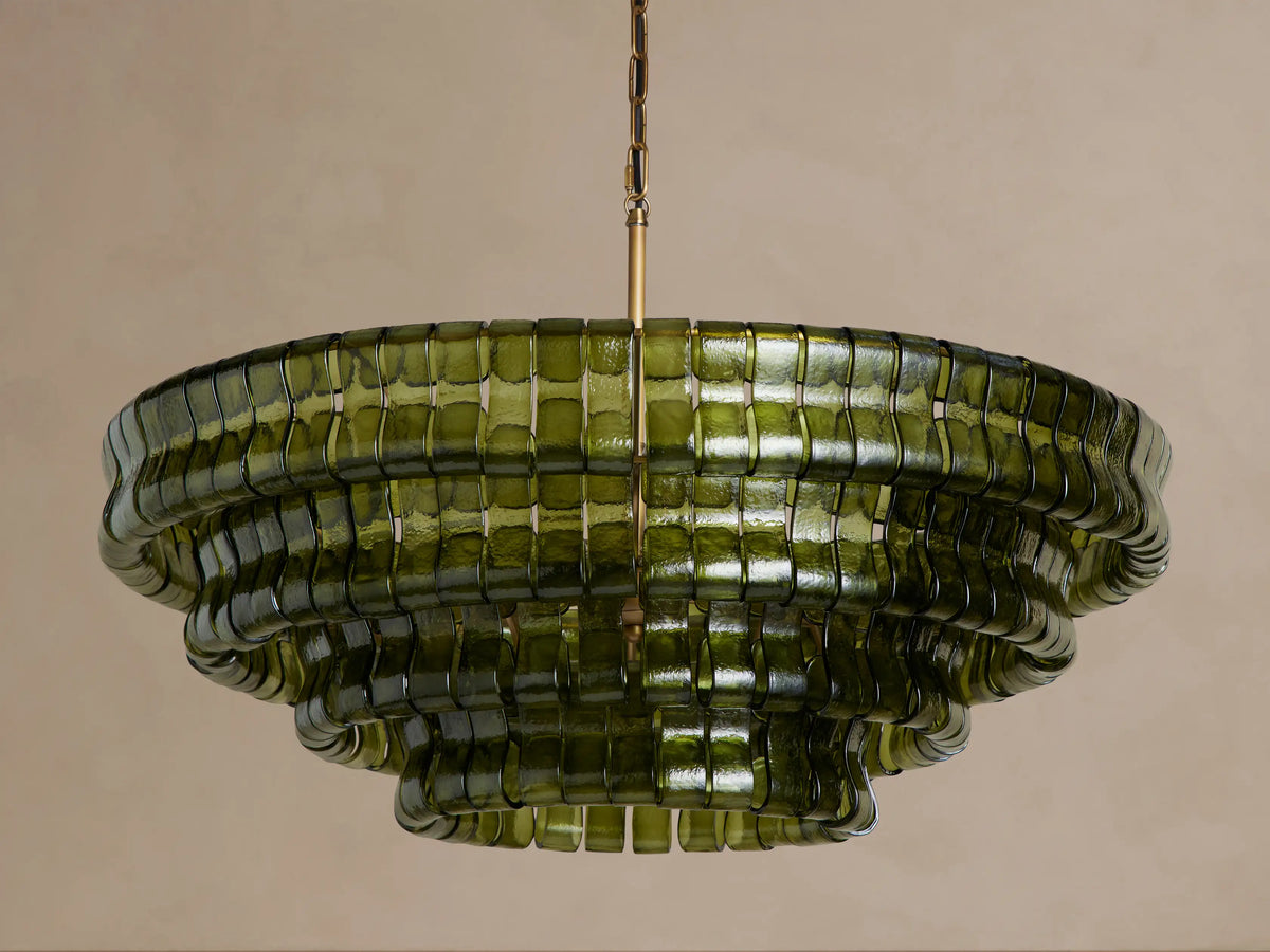 Ghiaccio Round Chandelier, dark green curved glass in tiered wavy layers, illuminated with warm golden light, hanging from chain.