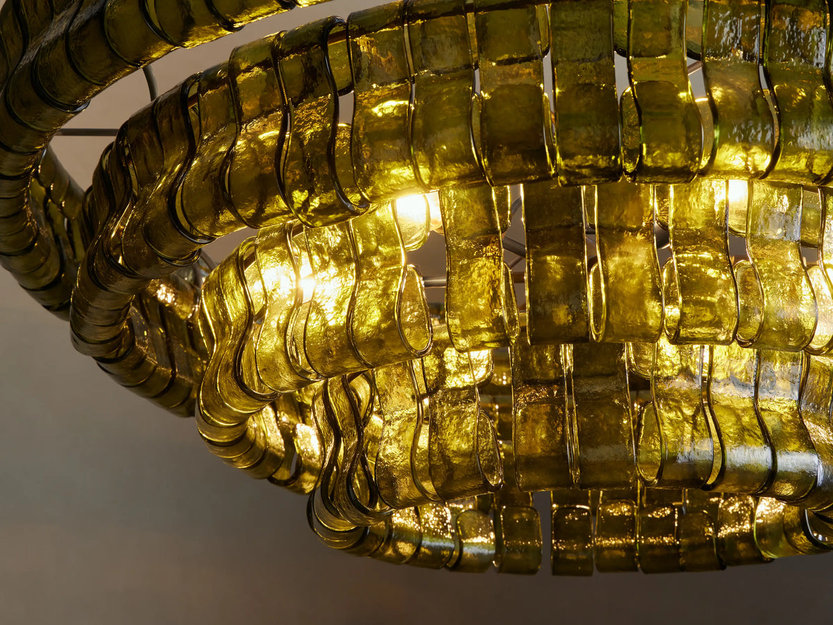 Round Ghiaccio Chandelier with layered tiers of translucent dark green curved glass panels in an overlapping pattern, hanging.