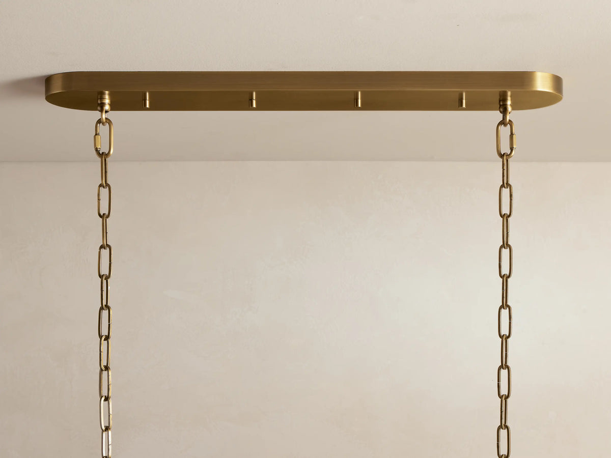 Ghiaccio Oval Chandelier close-up: textured, curved olive glass panels glow warmly, reflecting light in wavy forms.